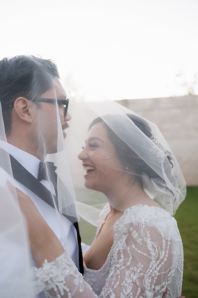 A bride and groom are smiling at each other